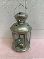 Front view of silver metal lantern with glass panels and star cutouts