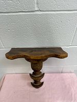 Front view of carved wood wall shelf showing overall shape