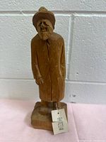 Full front view of carved wooden figure on base