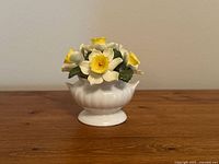 Front view of Ainsley fine bone china April daffodil floral arrangement on wooden surface against plain background
