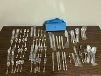 Full display of Birks Regency silver plate cutlery spread out on a table, showing all items included in the set for ten people and additional serving utensils.