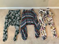 Three pairs of lightweight Buddha pants laid flat on the floor, showing colors and patterns side by side.
