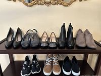 Front view of 8 pairs of ladies shoes arranged on a table including pumps, heels, flats, boots and sneakers