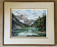 Framed oil painting showing a mountain lake scene with snowy peaks and pine trees, signed by Marion Barker.