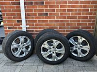 Four Michelin Defender TH all-season tires with Hyundai hubcaps on metal wheels