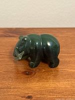 Side view of green nephrite jade bear holding fish with visible minor chip on fish's fin.