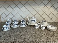 Full display of tea set on counter showing teapot, cups, saucers, creamer, sugar bowl, and plates with Nova Scotia Tartan pattern.