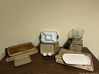 Full lot on table showing stoneware bar pan, white serving tray, small baking sheet, divided tasting dish, ramekins, and plastic storage combo.