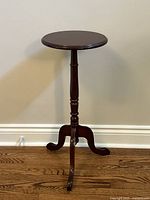 Full view of round top pedestal table with turned central column and three legs.