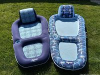 Both matching pool floats laid on grass side by side showing designs and headrests.