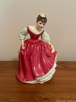 Front view of Royal Doulton Fair Maiden figurine in red dress, showing detailed facial expression and dress folds.