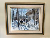 Framed oil painting depicting a winter sugar bush scene with two figures near a maple lodge and barrels in snow.