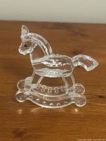 Front view of Swarovski crystal rocking horse figurine showing clear faceted crystal body and black and blue eyes.
