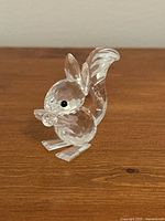 Clear crystal Swarovski squirrel figurine, viewed from left front angle on wood surface