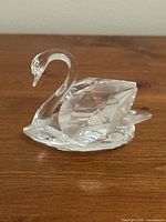 Side view of clear Swarovski crystal swan figurine showing faceted body and smooth neck.