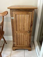 Front view of vintage pine jam cupboard showing door with vertical grooves, wooden knob, and silver hinges.