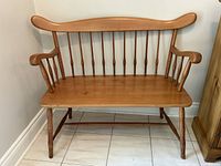 Front view of vintage Roxton solid pine wood bench showing contoured back, spindle supports, armrests, and turned legs.