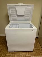 Front view of white Wood's chest freezer with lid open showing interior and basket.