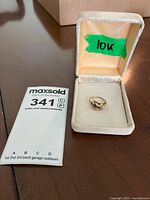 Ring inside beige cushioned jewelry box with '10k' label on the lid, showing overall look of the ring and box.