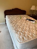 Full view of mattress on bed frame with folded linens on top.