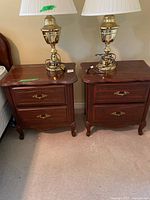 Pair of Andrew Malcolm wooden nightstands side by side, each with a brass lamp on top