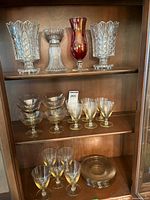Wide shot of all glassware including vases, sherbet and wine glasses, and plates on shelves
