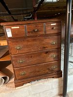 Full front view of the wooden dresser with all drawers visible, showing the general wear and the two top smaller drawers with wooden knobs and three larger drawers below with brass handles.