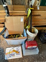 Electric fence supplies including box of insulators, wooden stakes, white bucket, energizers, and plastic containers