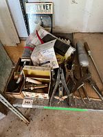 Photo of farm vet tools including hoof trimmers, metal syringe, veterinary handbook, and other assorted metal tools on a wooden pallet.