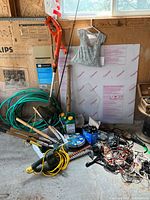 Photo showing various gardening tools including hedge trimmer, fishing rod, hose, hand tools, chargers, and cables.