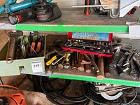 Photo showing assorted hand tools including hammers, wrenches, pliers on a green shelf with the red MIT socket set case on top held open revealing sockets and ratchets.