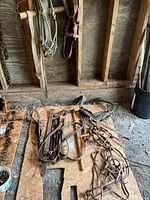 Overview of various horse tack and harness pieces laid on a wooden board including bridles, reins, and leather straps.