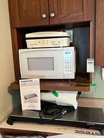 Lot showing Danby microwave on shelf, Hamilton Beach grill on top, and Toastess plate warmer below with manual