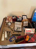 Lot of men's wristwatches, travel alarm clock, cufflinks, safety razor, grooming brushes, and other small accessories displayed on a table.