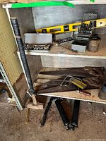 Shelf showing sledgehammer, socket set, wrenches, spirit level, drill bits, and grease tool.