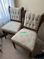 Pair of Eastlake chairs with button tufted backs and floral upholstery placed by a window.