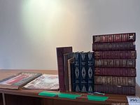 Side view of stacked vintage books and magazines with visible bindings, including hardcovers in maroon, blue and brown.