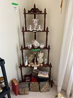 Full view of wooden corner shelf with decorative spindles and finials, displaying various items on shelves for size context.