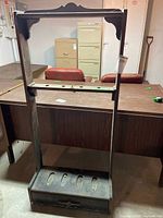 Full view of the vintage wooden display cabinet showing open frame, carved top detail, locking bar, and bottom drawer.