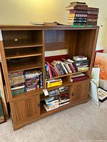 Wide view of the wooden entertainment center filled partially with books and DVDs, showcasing the overall structure and design.