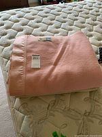 Pink wool blanket folded on mattress, label present