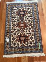 Full view of one small area rug showing geometric star medallions and floral borders on hardwood floor