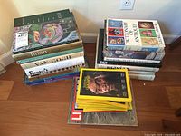 Wide view of all stacked art books on floor showing titles and variety