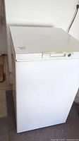 Full front and side view of white upright chest freezer showing overall condition and structure.
