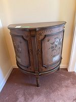 Front view of the semi-circular cupboard showing two doors with floral and butterfly hand-painted designs and decorative wood molding.