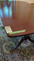 Photo showing polished wooden surface and corner of vintage dining table with size label (57x38x30 inches).