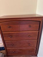 Front view of a wooden dresser with four drawers showing wooden knobs and medium brown finish.