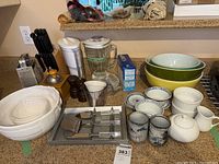 Full lot view showing large white ceramic bowls, clear glass jars, pepper mills, Pyrex ramekins, and various small bowls and dishes.