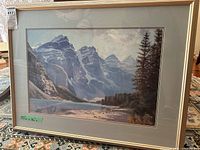 Framed landscape print featuring snow-capped mountains and a reflective lake. Green mat and simple frame visible. Size label 33 x 26 inches on glass.
