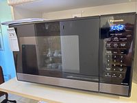 Full view of Panasonic microwave on countertop with label showing model and brand